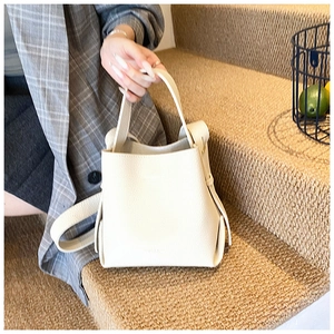 Détail du sac seau blanc en cuir grainé avec poignée supérieure sur fond naturel