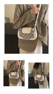 Detailed view of polka dot baguette bag featuring a pearl heart charm and bow accents