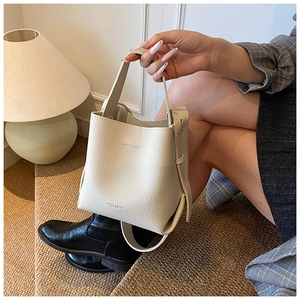 Détail du sac seau en cuir grainé crème avec poignée supérieure et bandoulière amovible
