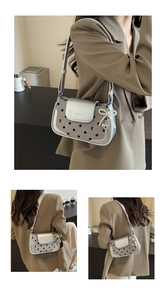 Close-up of silver polka dot baguette bag with pearl bow and heart pendant detail