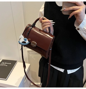 Détail d'un sac en cuir vintage marron foncé avec un charmant cheval à bascule bleu et blanc
