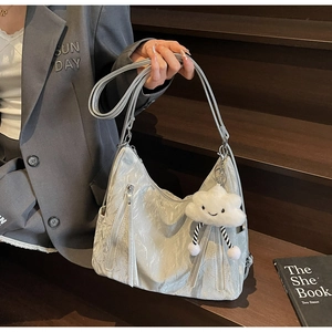 Detail of silver metallic textured shoulder bag with plush cloud charm and zippers