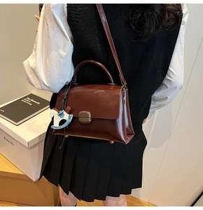 Détail du sac fourre-tout en cuir mat marron foncé avec un charmant poney bleu décoratif