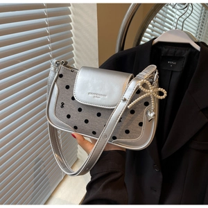 Close-up of silver polka dot baguette bag with pearl bow charm and heart metal pendant