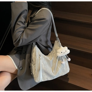 Detail of white pleated hobo bag with zip pockets and cute cloud plush pendant