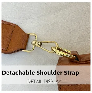 Macro view of the detachable shoulder strap with golden metal hook on brown leather bag