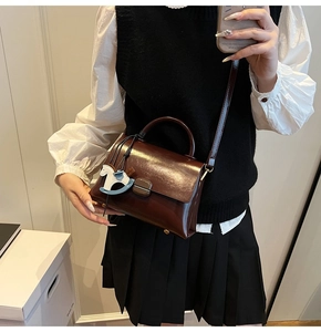 Détail du sac cabas en cuir marron foncé avec breloque cheval et fine bandoulière