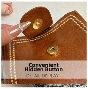 Detail of the magnetic snap closure on a brown faux leather bucket bag with gold embroidery