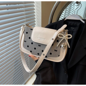 Detail of polka dot baguette bag featuring pearl bow charm and heart metal pendant