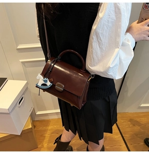 Sac fourre-tout en cuir marron foncé avec charm cheval à bascule porté par un mannequin