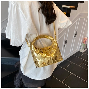 Détail d'un sac à main tissé doré avec poignée incurvée porté par un mannequin femme