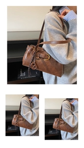 Detail of vintage brown faux leather shoulder bag with buckle and woven ring charm