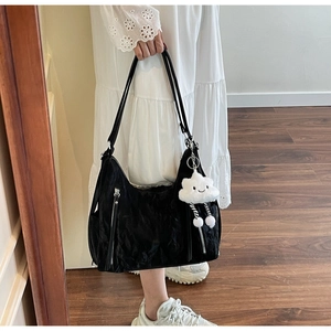 Detail of black pleated tote bag with white cloud plush charm and silver zippers