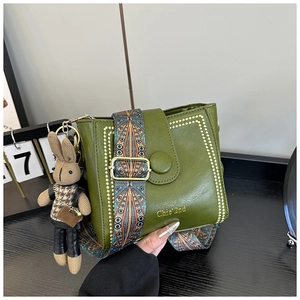 Detailed view of olive green leather bucket bag with ethnic strap and rabbit charm