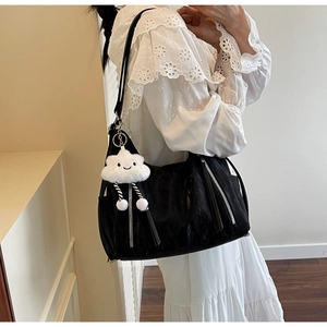 Detail of a black nylon shoulder bag with luxury zippers and a cute plush cloud charm