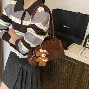Vintage brown leather shoulder bag with a cute plush bear pendant shown on model