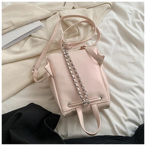 Detailansicht einer rosa PU-Lederhandtasche mit Silberkette auf einem Bett-Szenario
