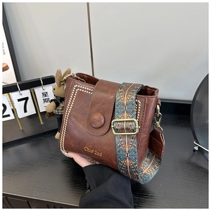 Close-up of retro brown bucket bag with ethnic strap and gold studs detail