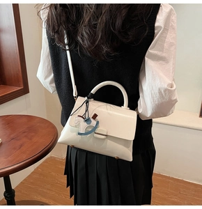 Détail du sac à main blanc en cuir avec poignée incurvée et un pendentif cheval