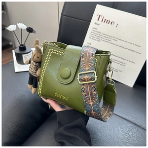Close-up of green leather crossbody bag with ethnic woven strap and cute bunny charm
