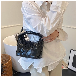 Gros plan d'un sac hobo en cuir tressé noir brillant porté par un mannequin