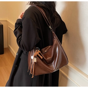 Detalle del bolso hobo marrón oscuro con borlas de cuero y acabado brillante