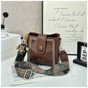Detail of vintage brown leather bag with ethnic printed wide strap and rabbit charm