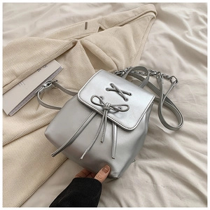 Detail der silbernen Metallic-Handtasche mit Kreuzschnürung und 3D-Schleifendekor