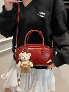 Fashionable dark red crossbody bag with plush bear charm and glossy leather finish