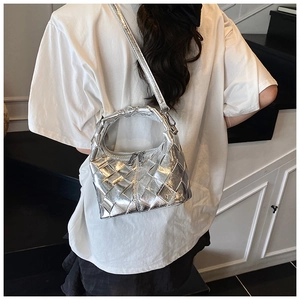 Sac bandoulière tressé argenté au fini métallisé porté par un mannequin en intérieur