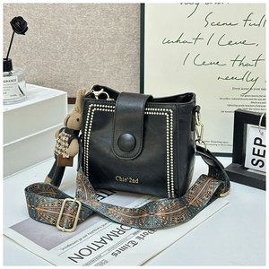Detail of black leather bucket bag with gold studs and bohemian jacquard strap