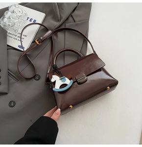 Détail du sac cabas marron foncé avec texture en cuir et breloque cheval design