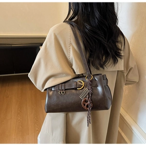 Detail of dark brown retro shoulder bag with belt buckle and pretzel pendant charm