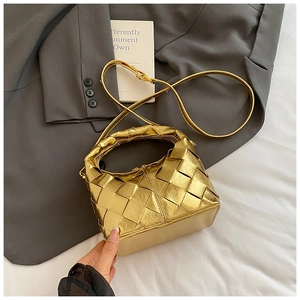 Détail d'un sac bandoulière tressé doré posé sur une veste de tailleur grise