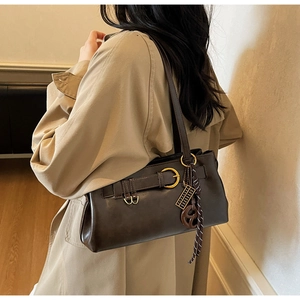 Detail of dark brown leather shoulder bag with vintage gold ring and abacus charm