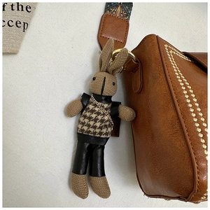 Close-up of knit rabbit charm and geometric embroidered strap on a retro bucket bag