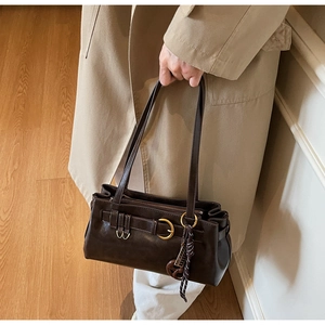 Detail of dark brown vintage pillow bag with oil wax leather texture and metal buckle