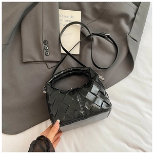 Vue de dessus d'un sac à main en cuir tressé noir avec bandoulière sur tissu blanc chic