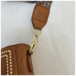 Detailed macro view of brown faux leather bag with vintage geometric strap and gold hardware