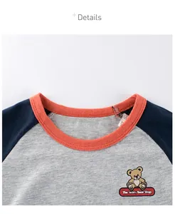 Détail d'un t-shirt enfant raglan avec col rond orange et broderie d'un ourson en peluche