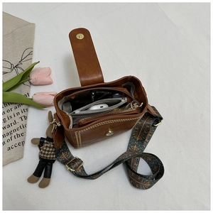 Top view of brown bucket bag interior showing multiple compartments and stylish strap