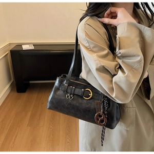 Detail of vintage black shoulder bag with gold hardware and stylish knot pendant