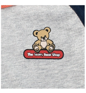 Détail de la broderie ours en peluche et coutures tricolores sur t-shirt gris enfant