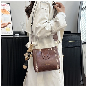 Detailed shot of brown vintage bucket bag with gold rivets and cute rabbit charm