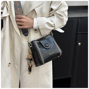 Detail of black bucket bag with gold studs and ethnic pattern wide shoulder strap