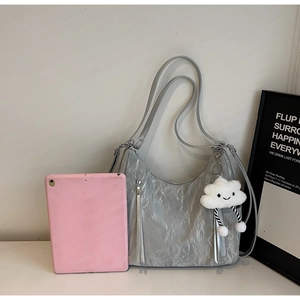 Close-up of silver pleated hobo bag featuring tassel zippers and a cloud plush charm