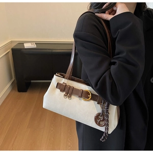 Detail of cream retro underarm bag with brown strap and gold buckle on a model