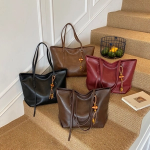 Large minimalist tote bags in four colors with bohemian tassel charms on stairs