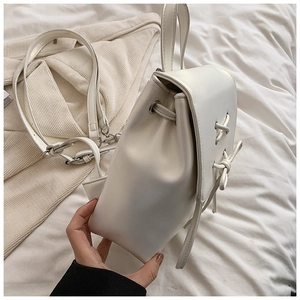 Details des weißen Kunstleder-Rucksacks mit Klappe und geknotetem Kordelzug-Design