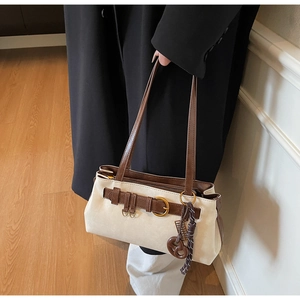 Detail of retro color-block handbag showing brown strap and gold metal buckle